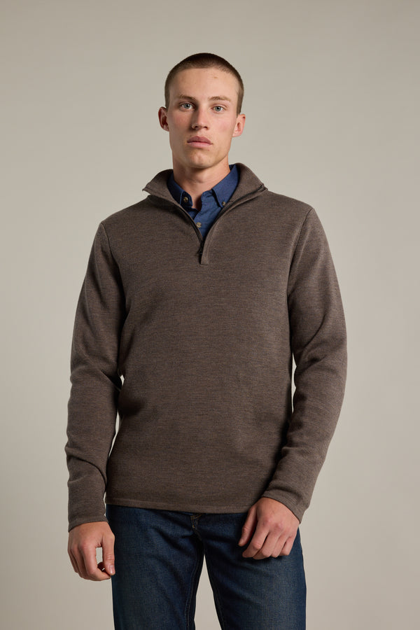 A young man with short hair wears the Barkers Brandon ZQRX Merino 1/4 Zip sweater over a blue collared shirt and jeans, standing against a plain light background and looking directly at the camera.
