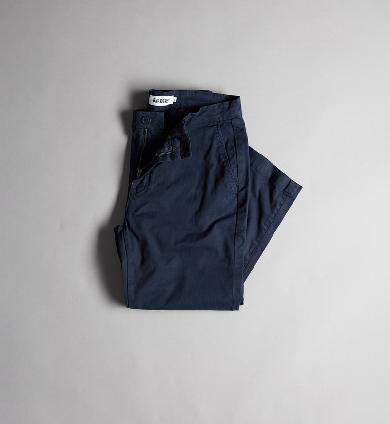 Folded navy blue NZ pants on a plain light gray background.