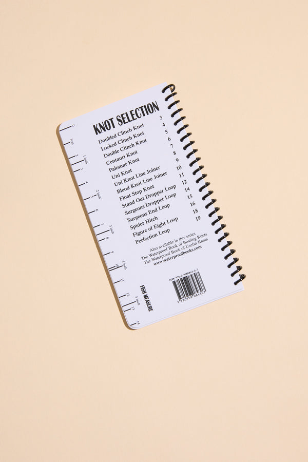A compact spiral-bound book titled "Fishing Knots" by Other is displayed on a light beige background, featuring top fishing knots and their page numbers on the back cover, plus a printed ruler along the left edge.