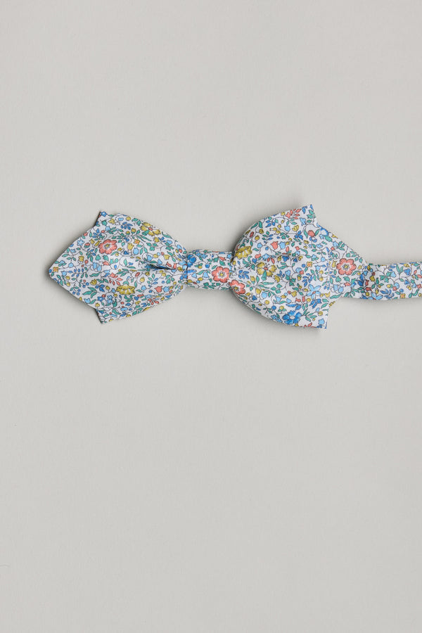 The Katie and Millie Liberty Bow by Liberty features a blue, yellow, and red floral pattern on luxurious Tana Lawn cotton, handmade in New Zealand and shown against a light gray background.