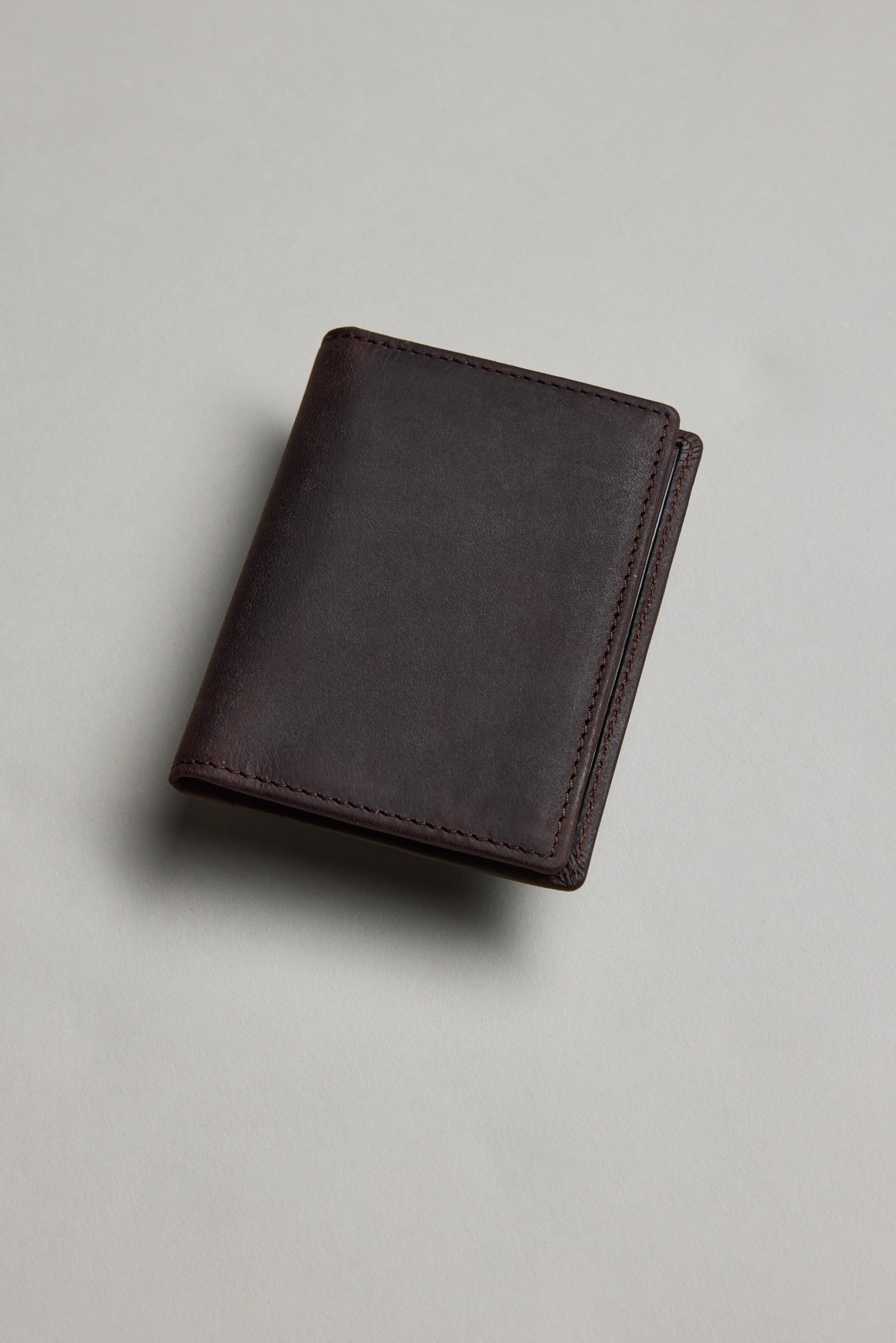 The Barkers Marlin Leather Slim Wallet, made from premium dark brown cowhide, sits closed on a light gray surface with soft lighting creating a subtle shadow.